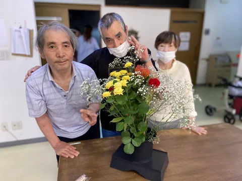 花を飾ったテーブルを囲んで並ぶ三人